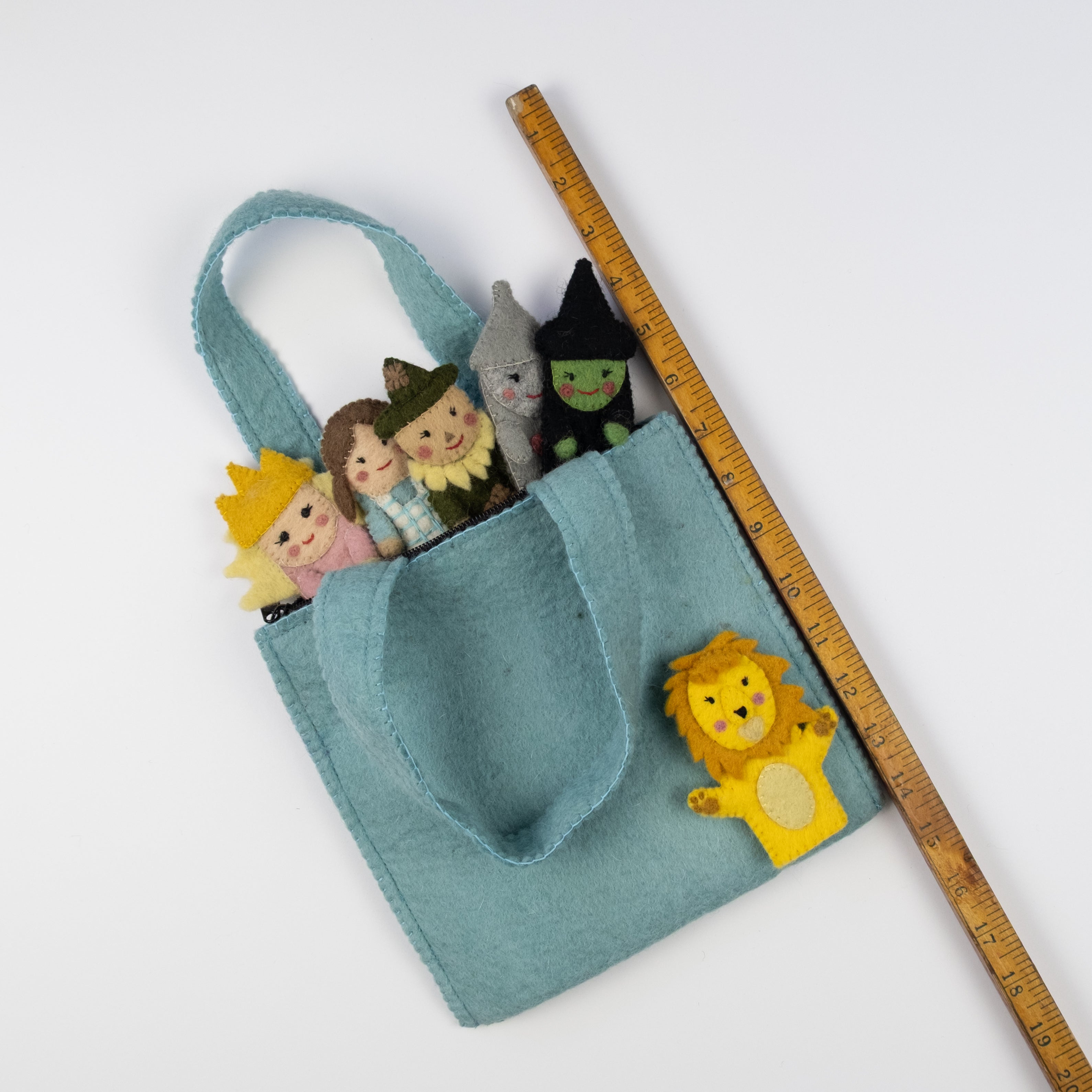 Small blue felt bag with finger puppets and a lion plushie, next to a wooden ruler for scale. Handmade. | Global Goods Partners