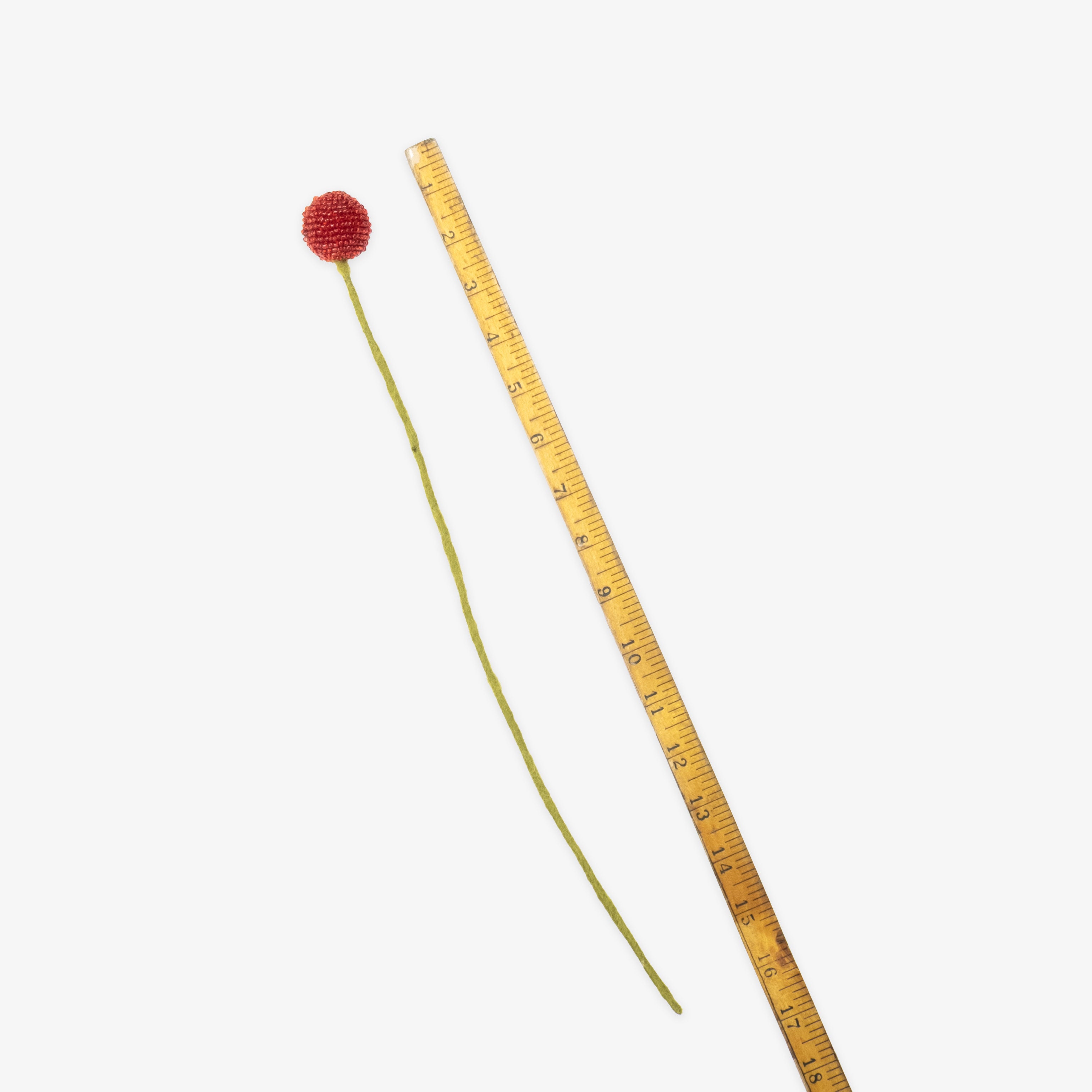 Handmade fair trade floral stem with red bloom and green leaves next to a ruler for scale on a white background | Global Goods Partners