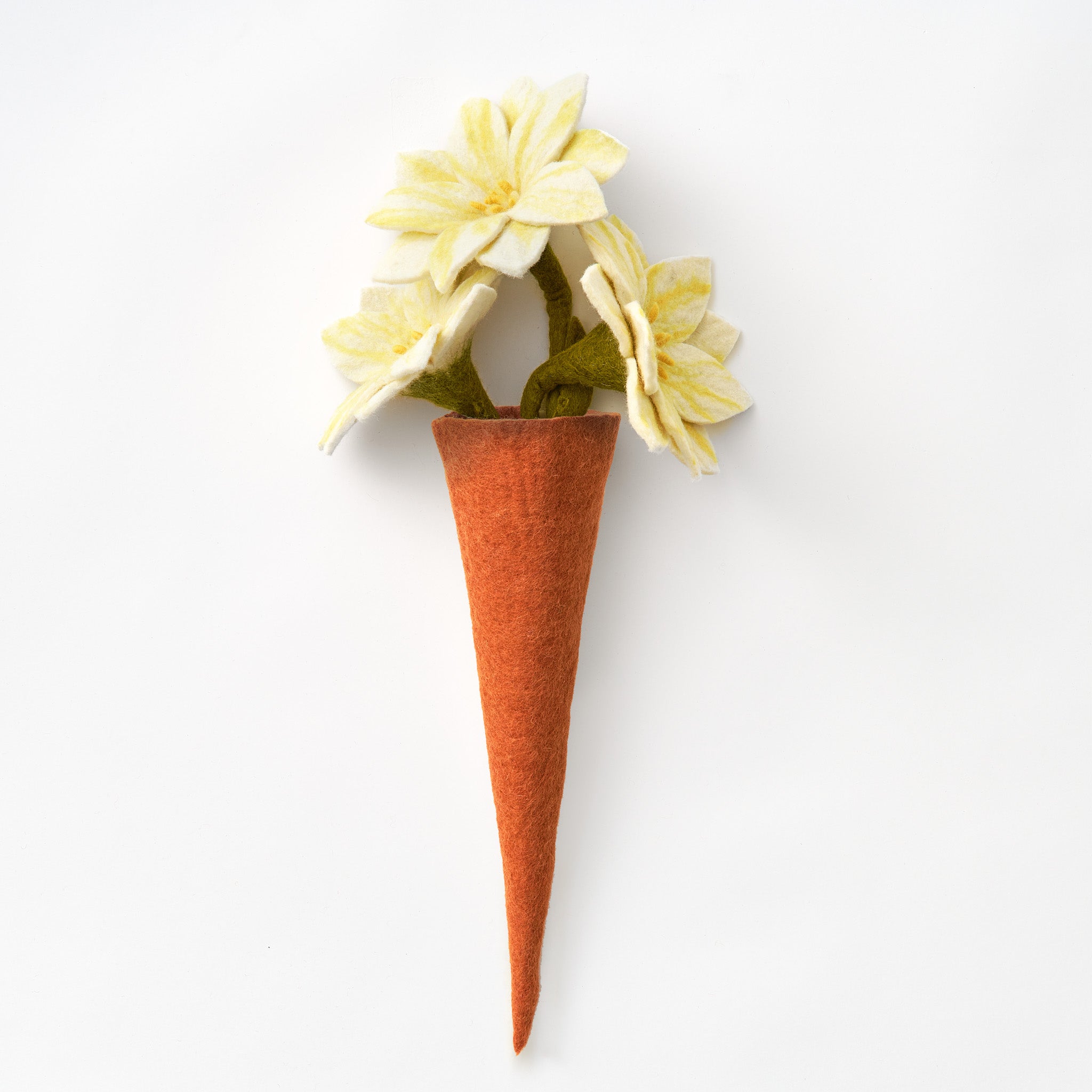 A handmade, fair trade felt vase in a warm rust-orange color, styled with three pale yellow felt flowers and green stems, set against a plain white background | Global Goods Partners