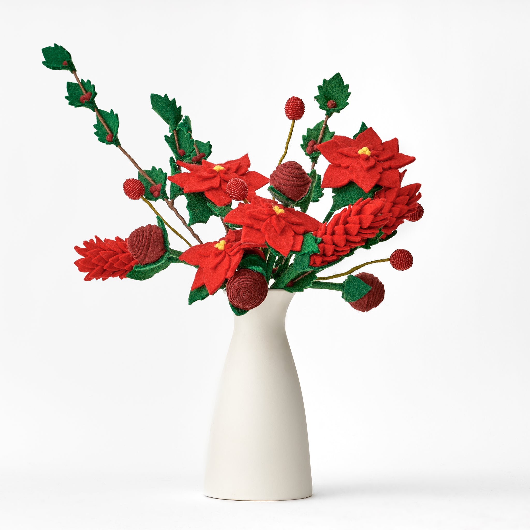 Decorative arrangement of felted handmade red and green flowers in a white vase on a white background. Bouquet made by women artisans in Nepal | Global Goods Partners