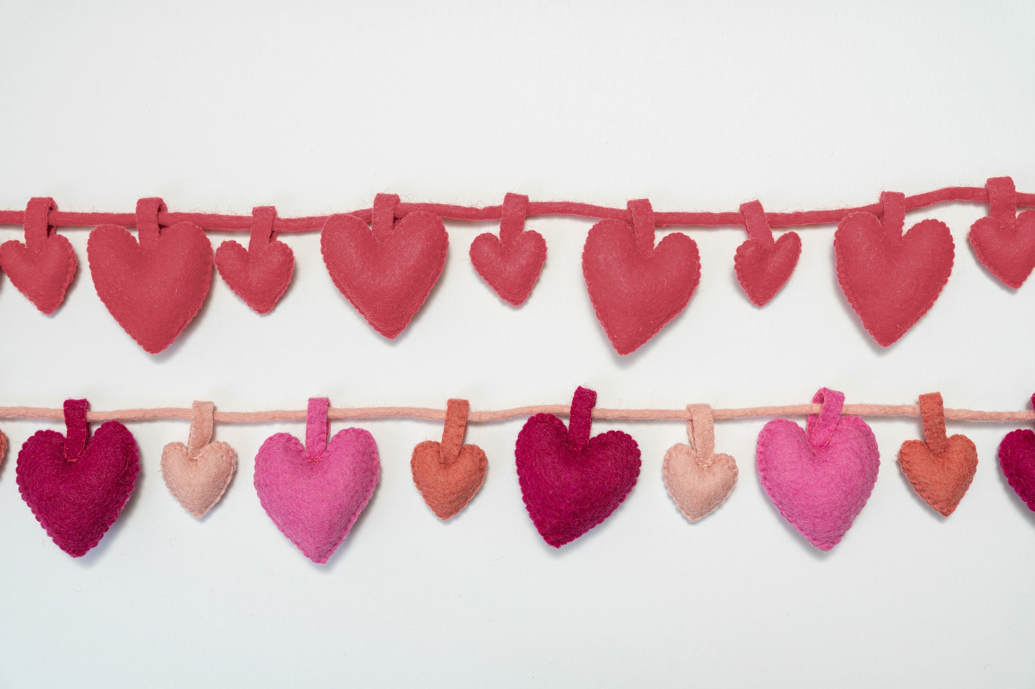 Felt heart garland in various pinks on a white background. Handmade by women artisans in Nepal | Global Goods Partners