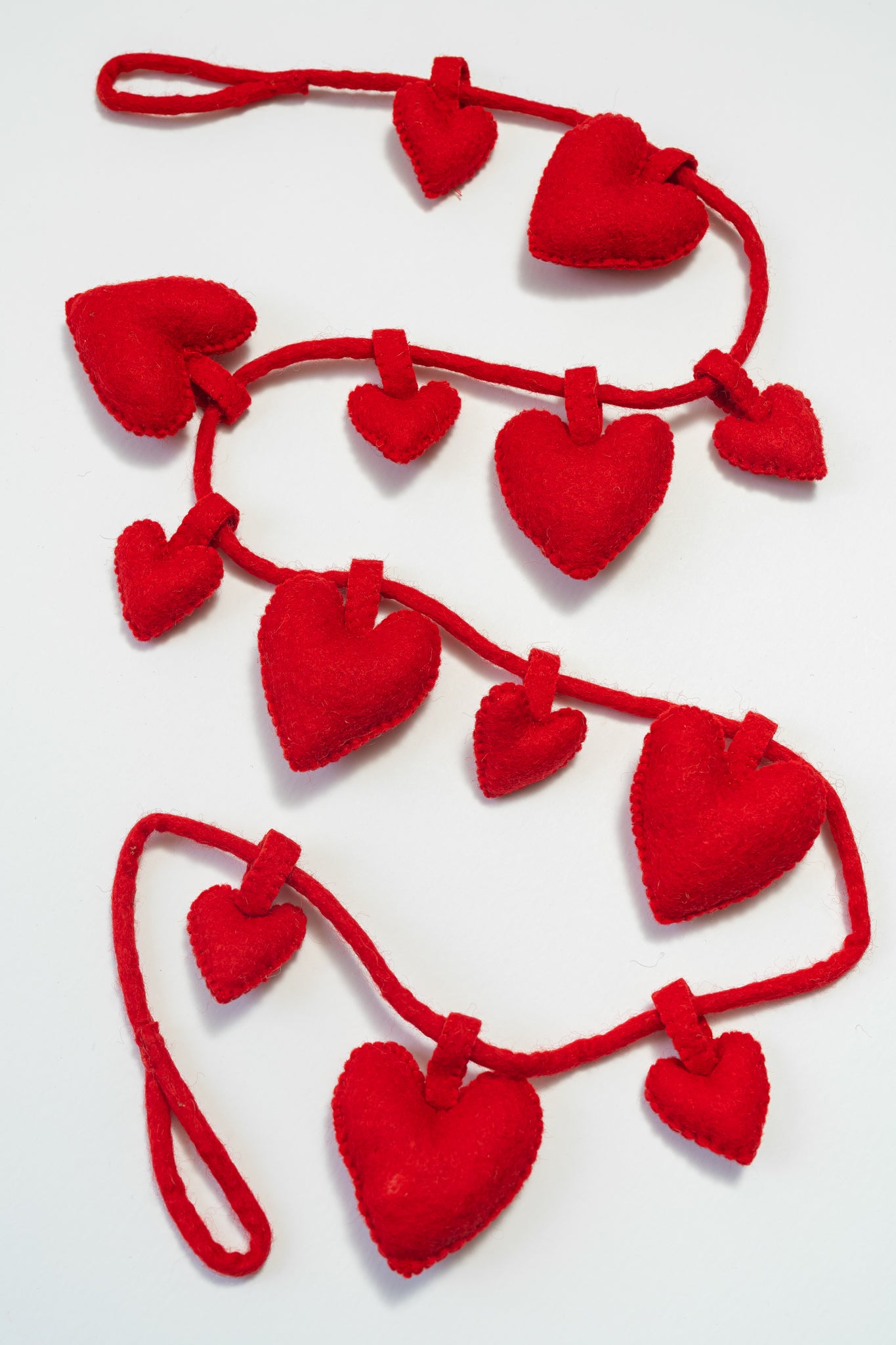 Red heart-shaped garland on a white background, garland handmade by women artisans in Nepal | Global Goods Partners