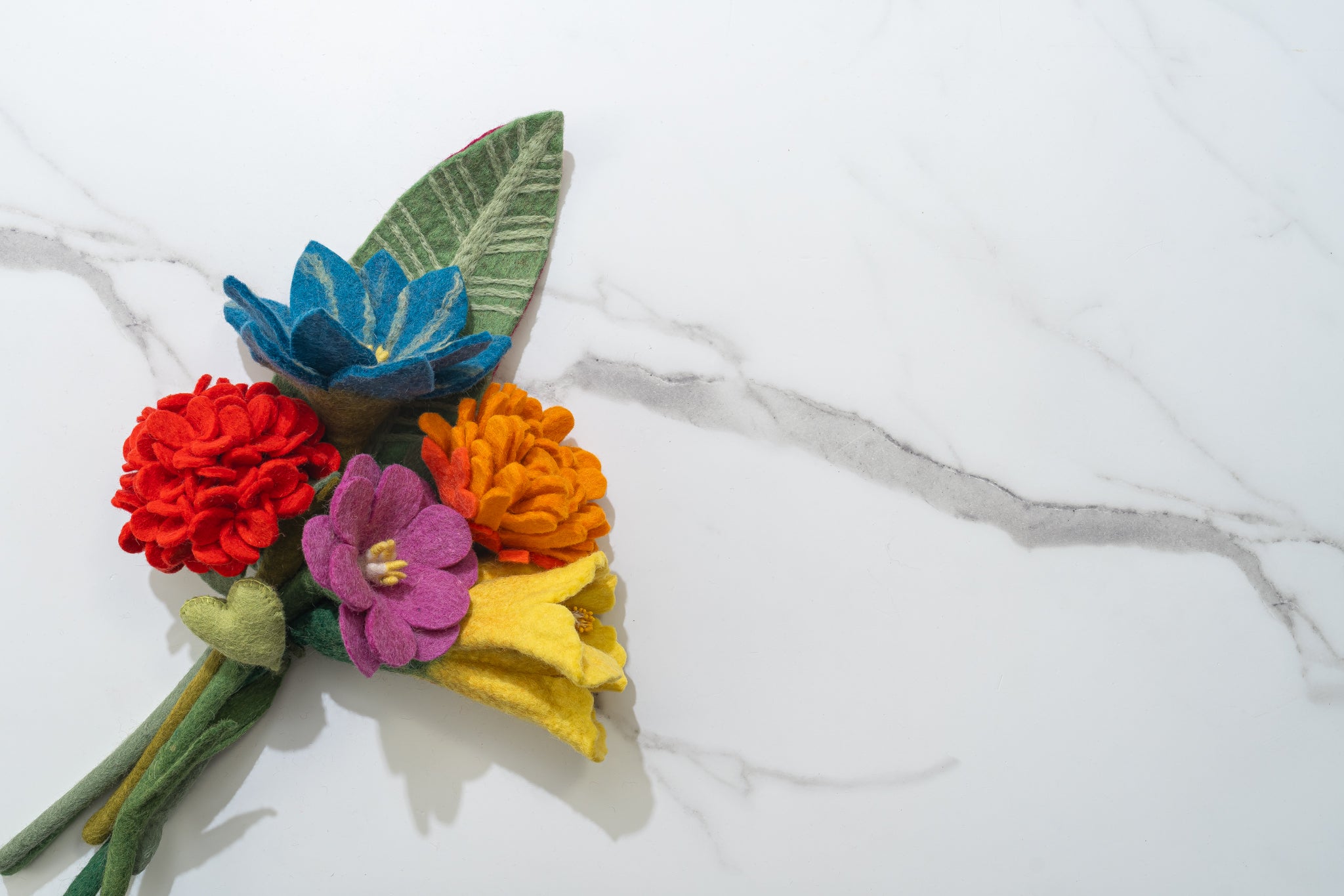 Colorful, vibrant felt flower arrangement on a marble surface, flowers handmade by women artisans from Nepal | Global Goods Partners