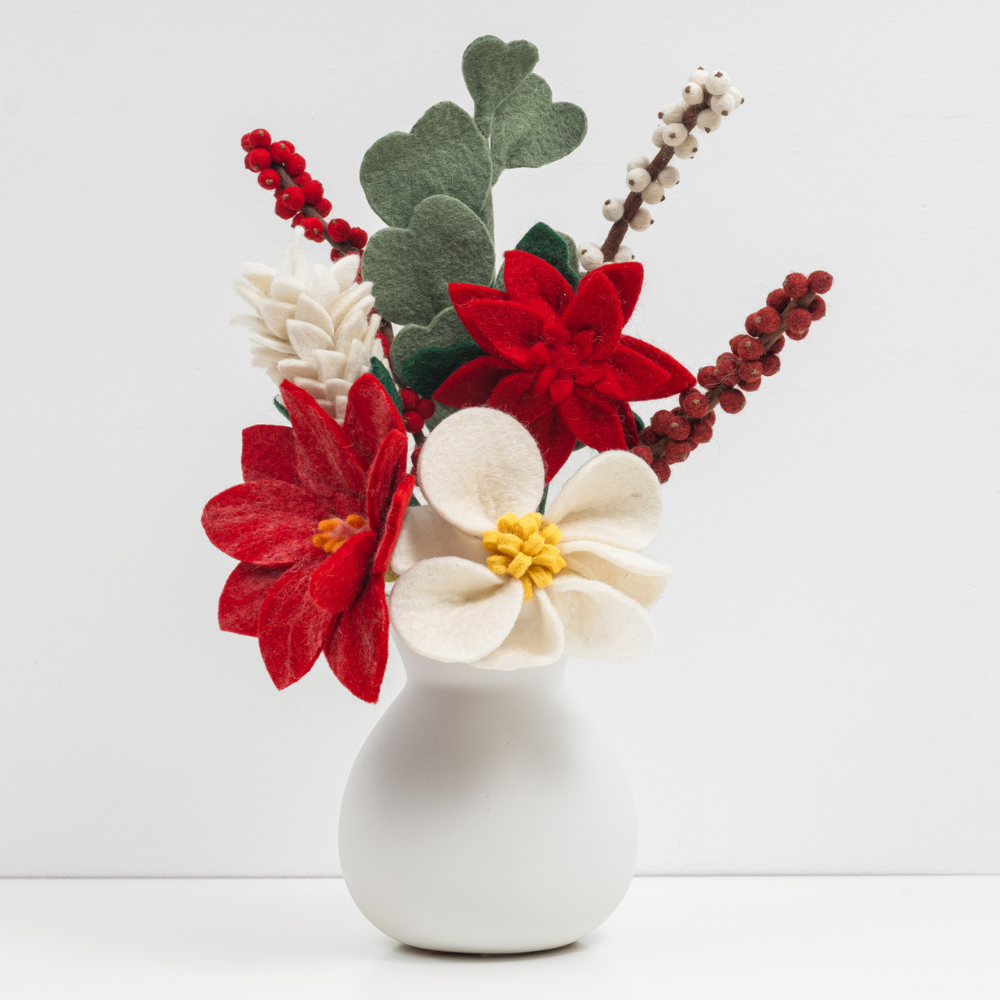 Decorative felt flower arrangement in a white vase on a light gray background, handmade by artisans and fair trade