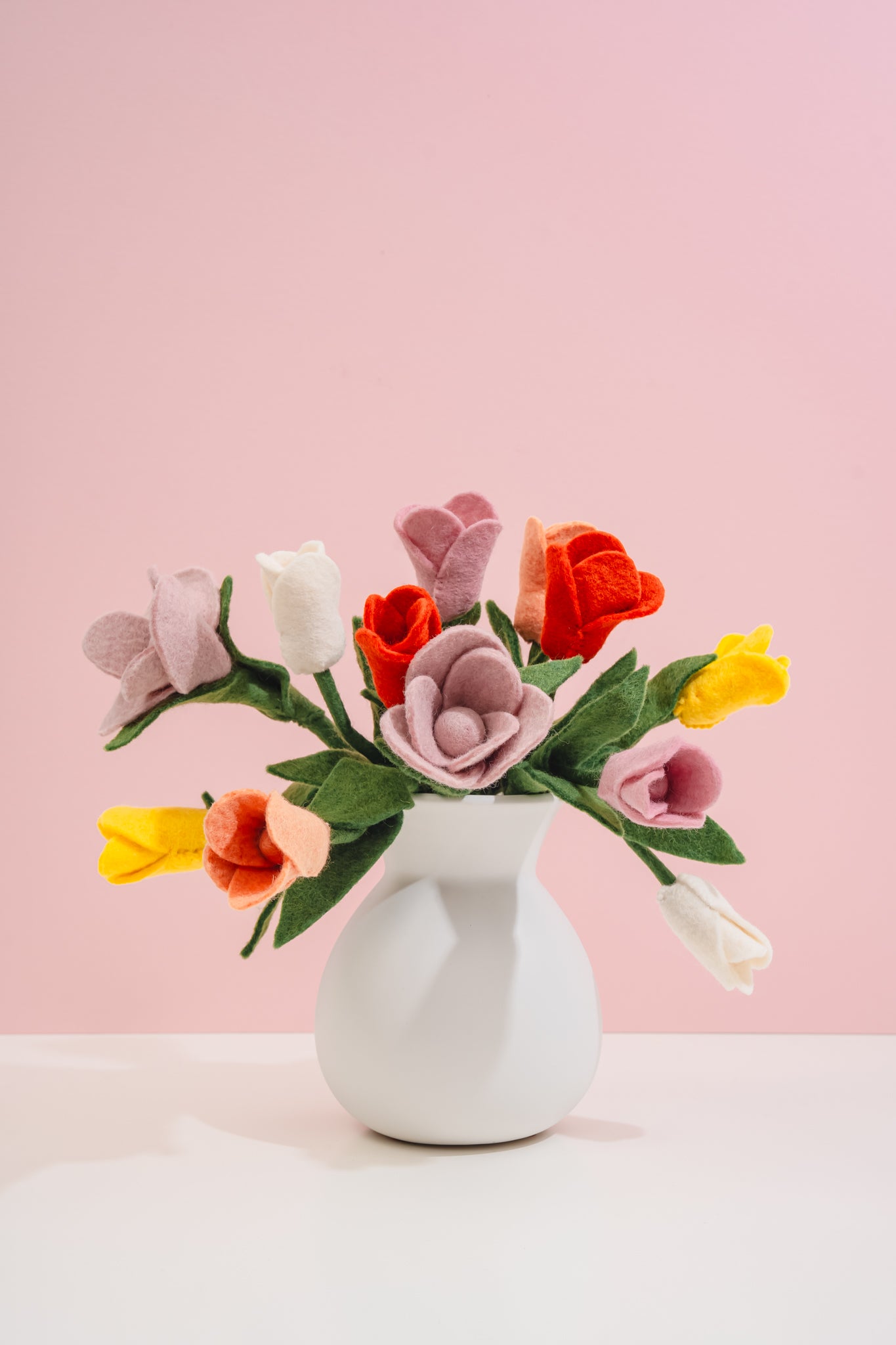 Felt flower bouquet in a white vase on a pink background made by women artisans in Nepal | Global Goods Partners