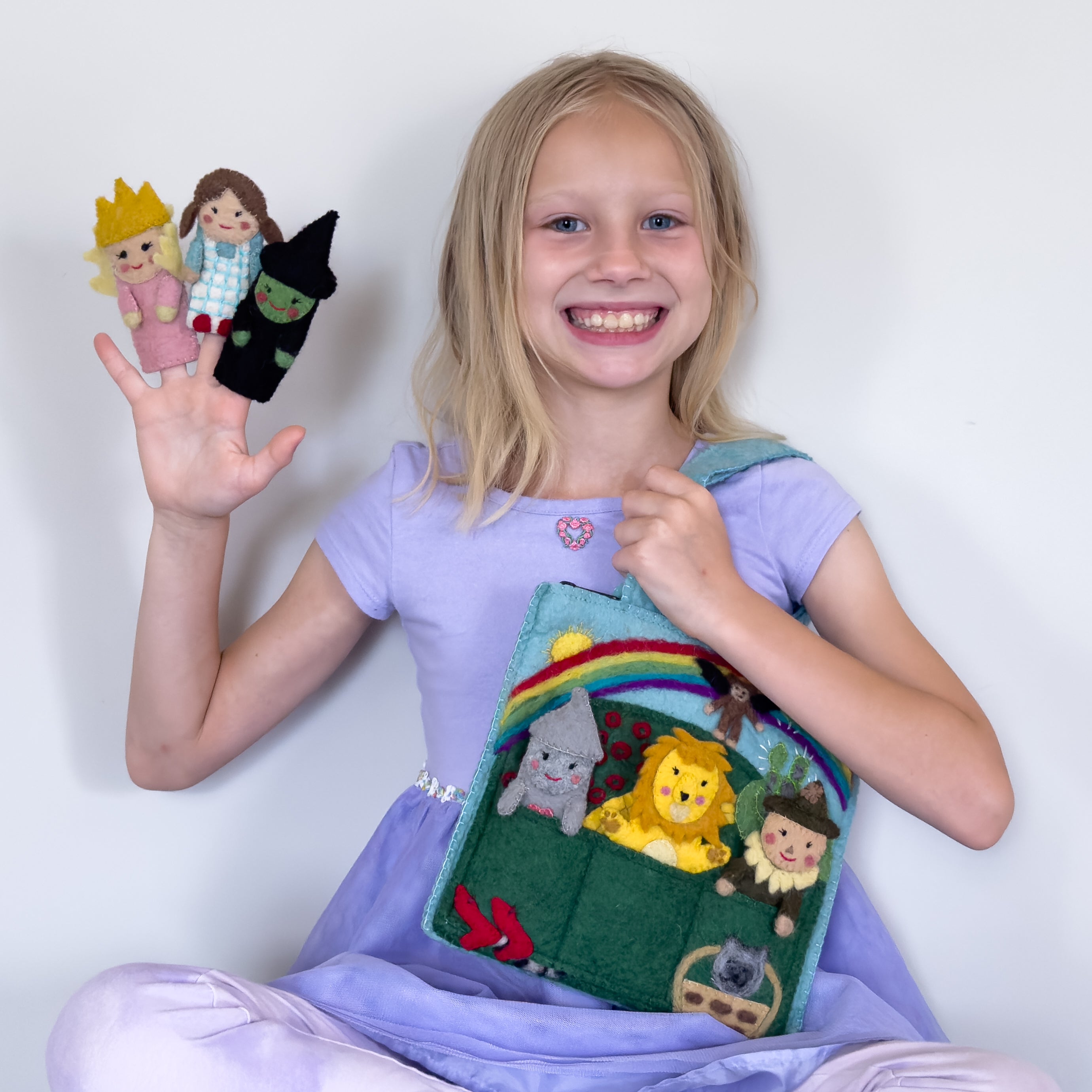 Young girl holding a felt storytelling bag with characters and finger puppets. | Global Goods Partners