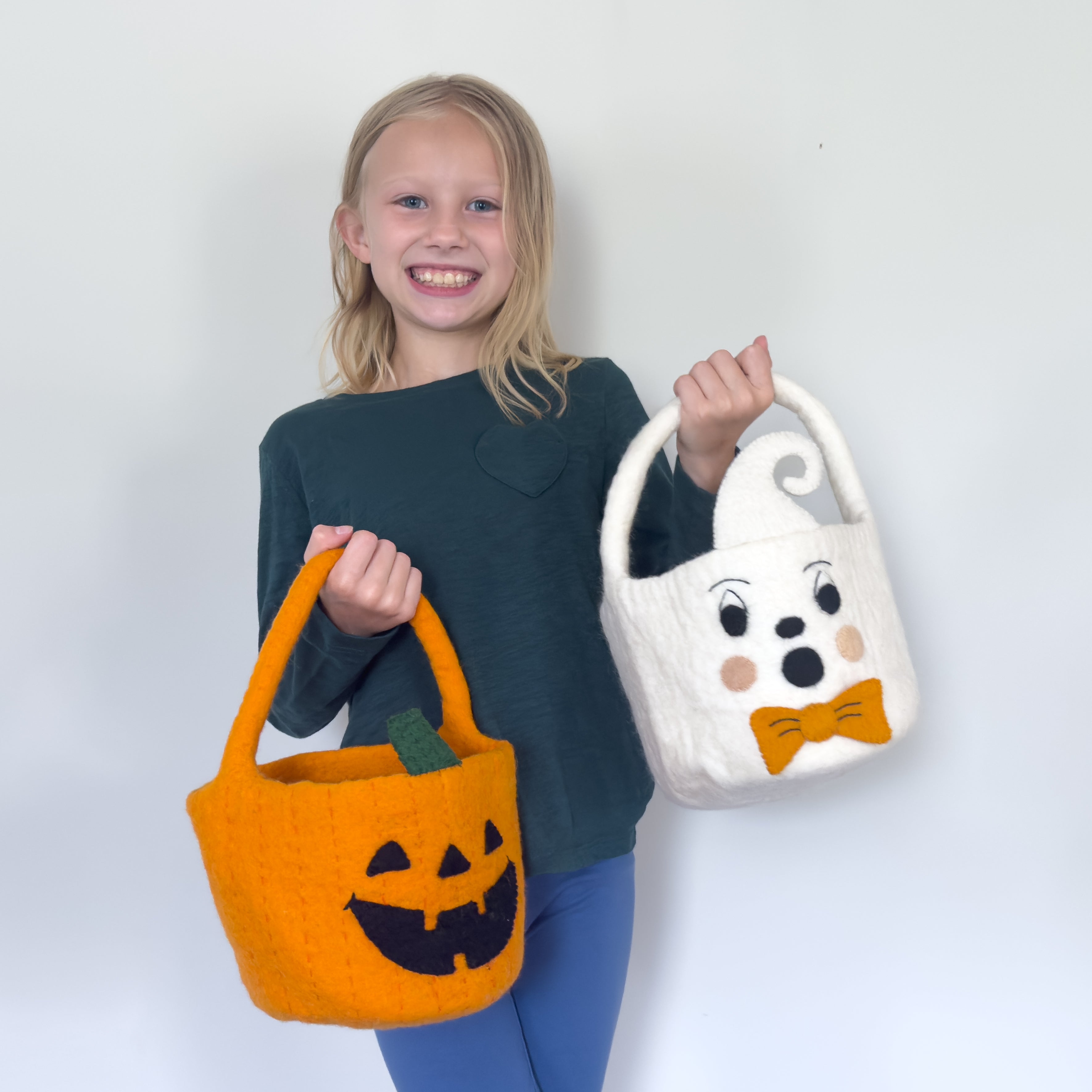 child holding 2 fair trade felt halloween trick or treat buckets