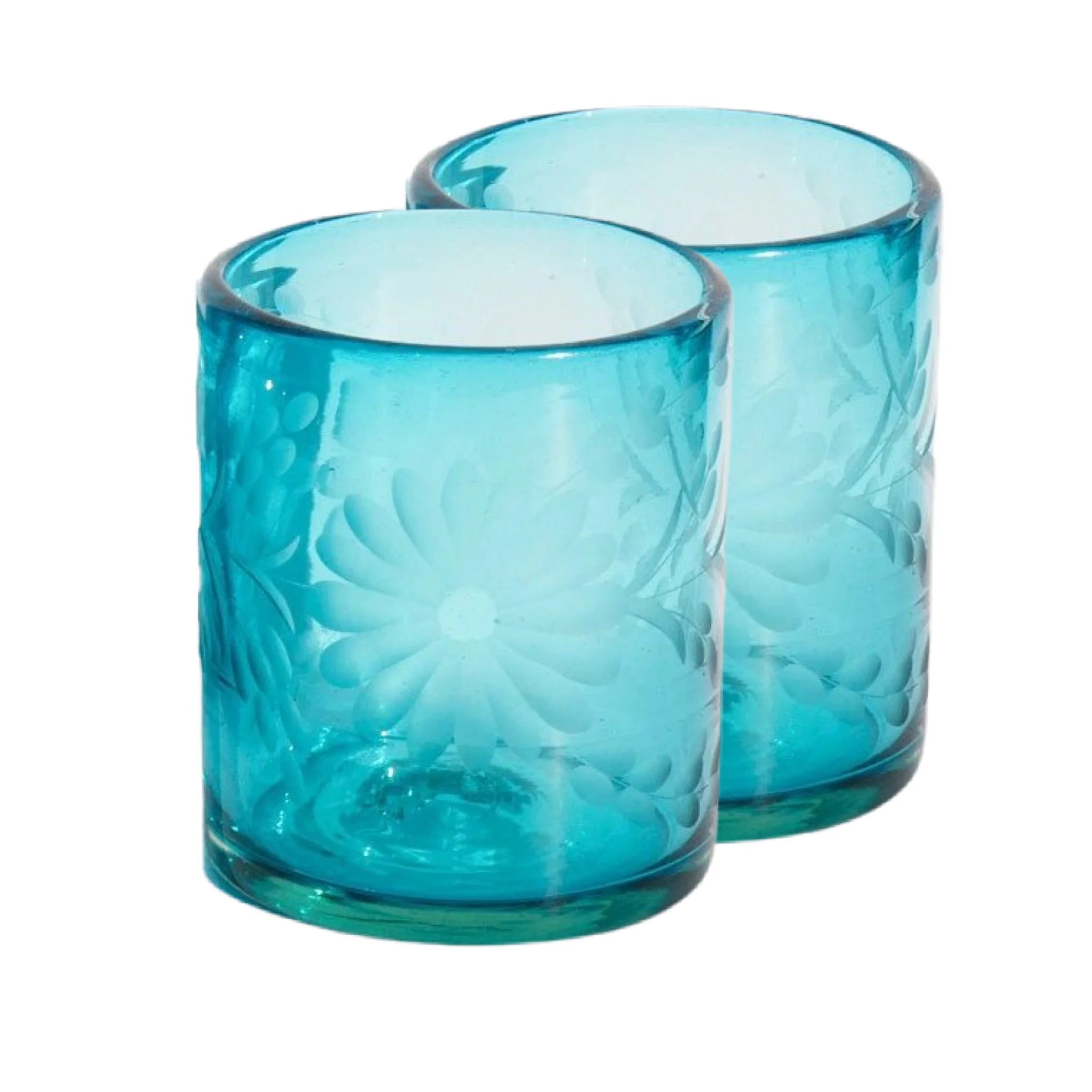 Two handblown turquoise aqua glass tumblers with embossed designs on a white background | Global Goods Partners