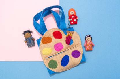Felt art palette with colorful paint swatches, felt dolls, and felt paintbrushes on a two-tone pink and blue background. Fair Trade & handmade kids gift | Global Goods Partners