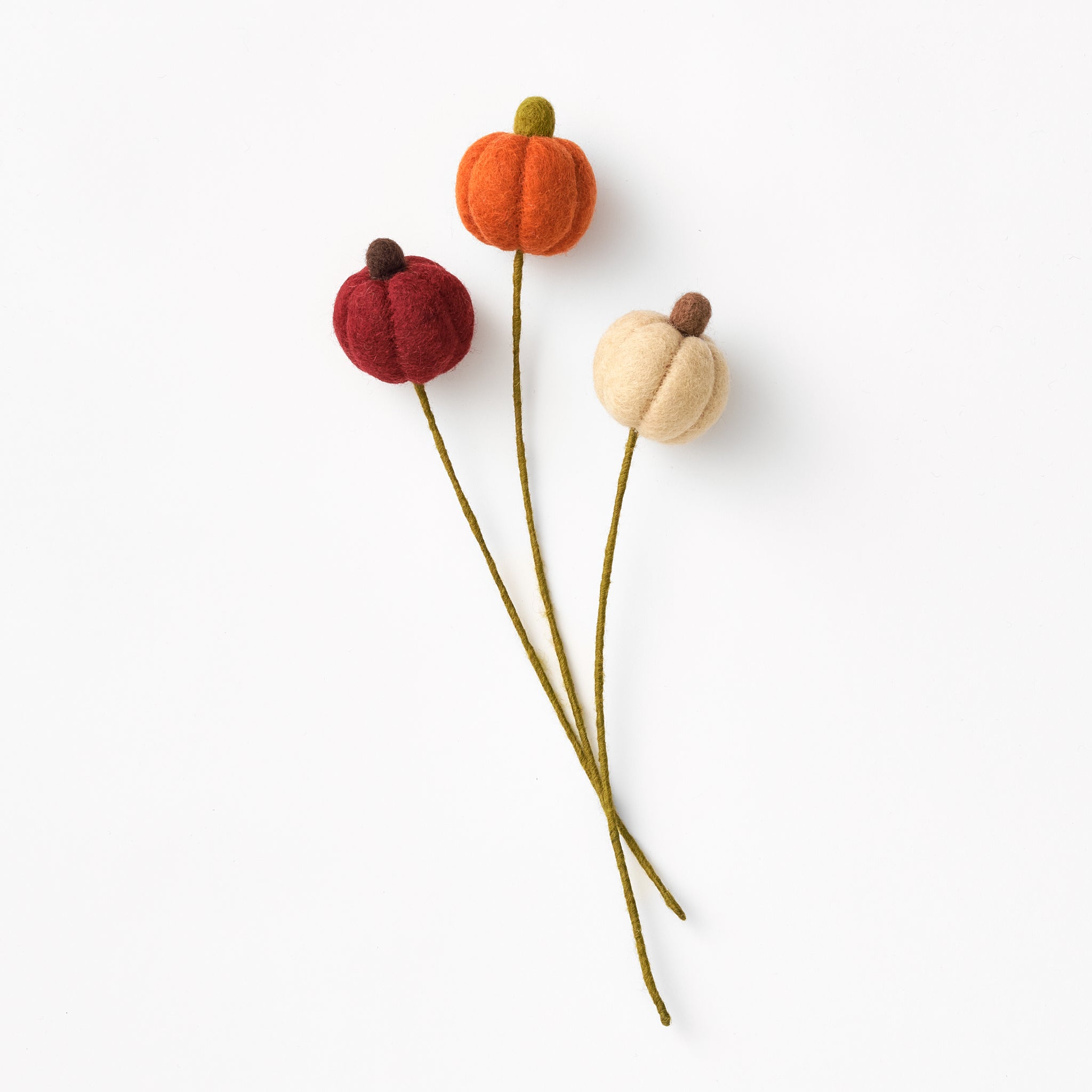 Three handmade felted pumpkin decorations on green stems against a white background | Global Goods Partners