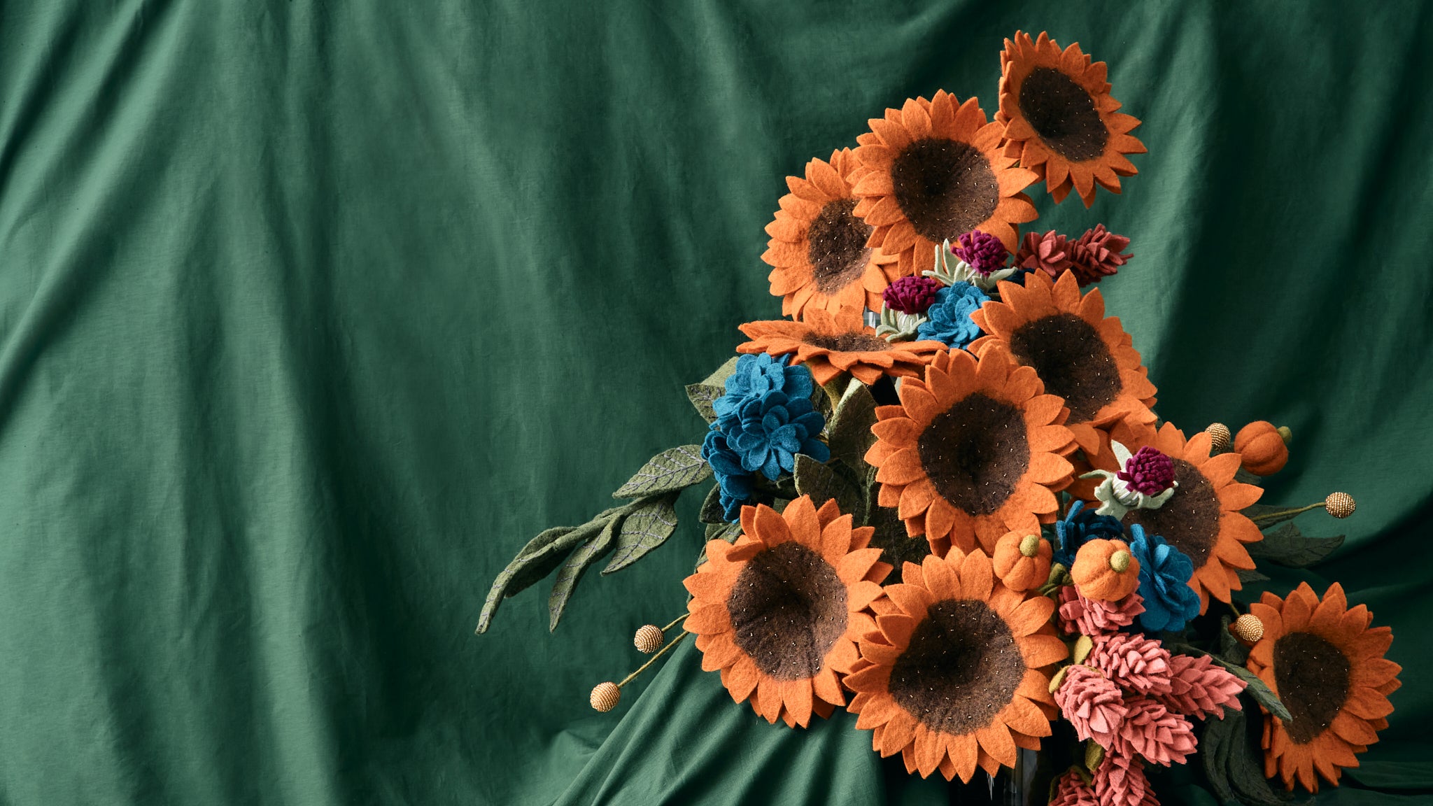Decorative arrangement of hand-felted flowers on a green fabric background. Artisans made & fair trade| Global Goods Partners