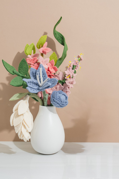 White vase with colorful felt flowers on a beige background, handmade by women artisans in Nepal | Global Goods Partners
