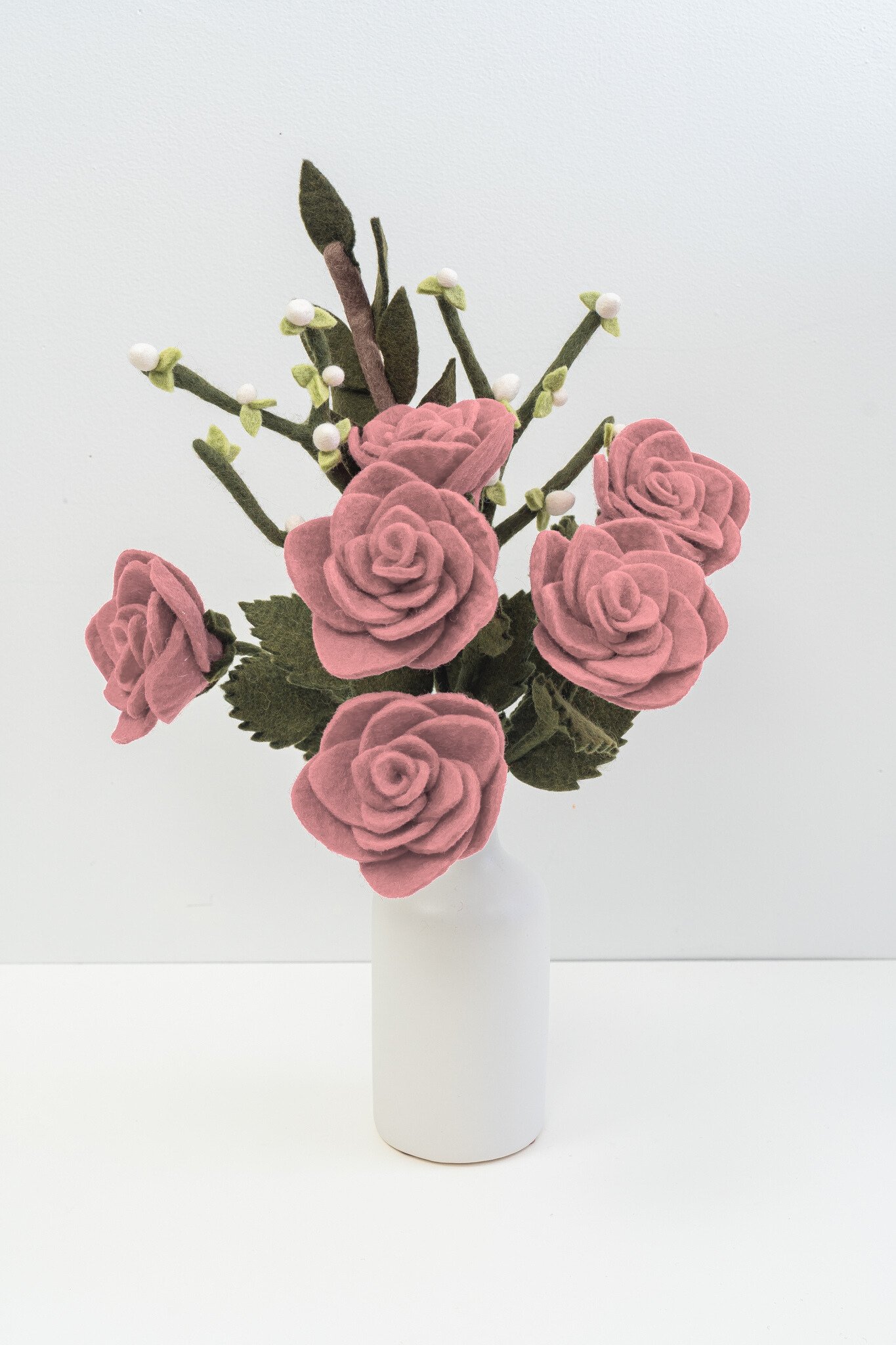 Bouquet of pink felt flowers in a white vase on a light gray background. Fair trade and handmade | Global Goods Partners