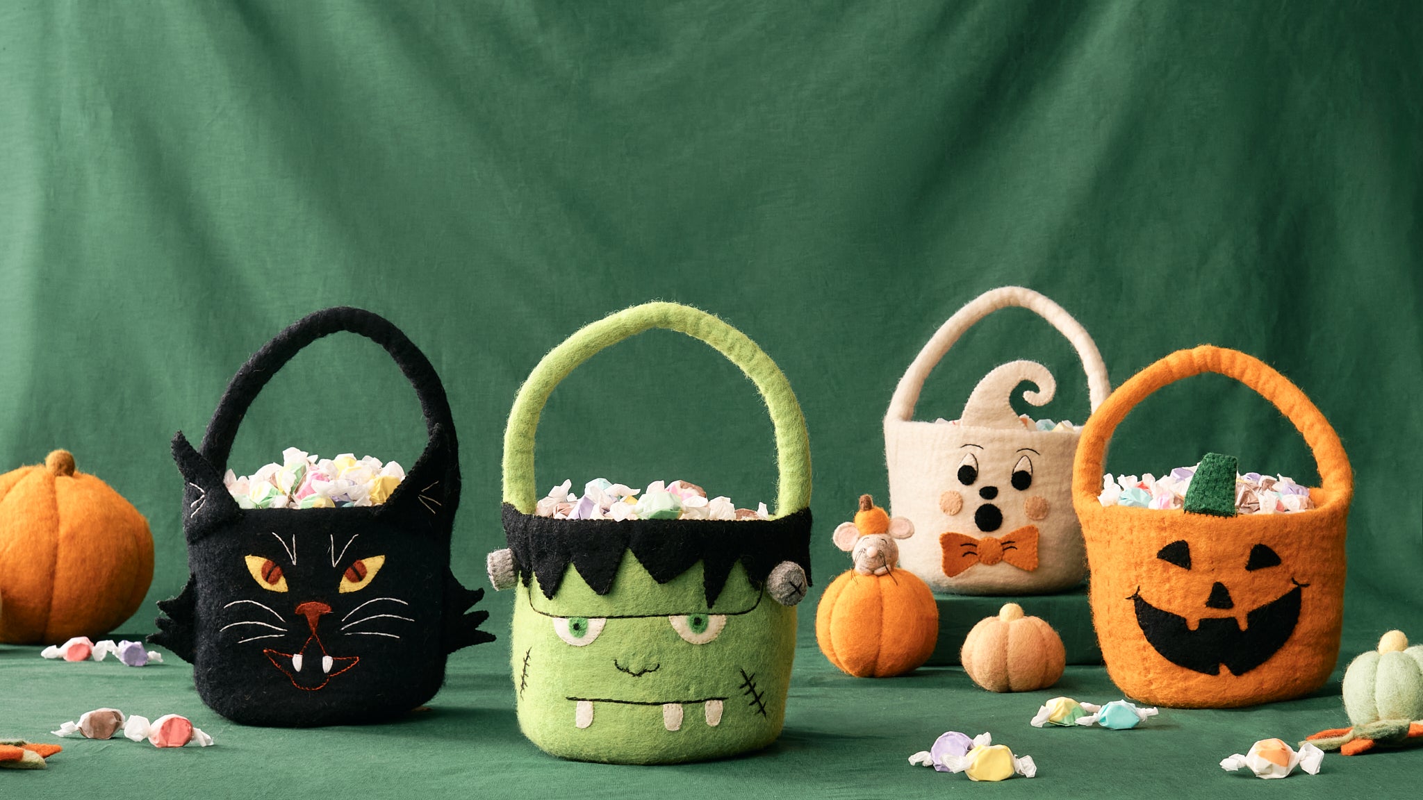 Four handmade, fair trade, felt Halloween-themed candy baskets on a green background | Global Goods Partners