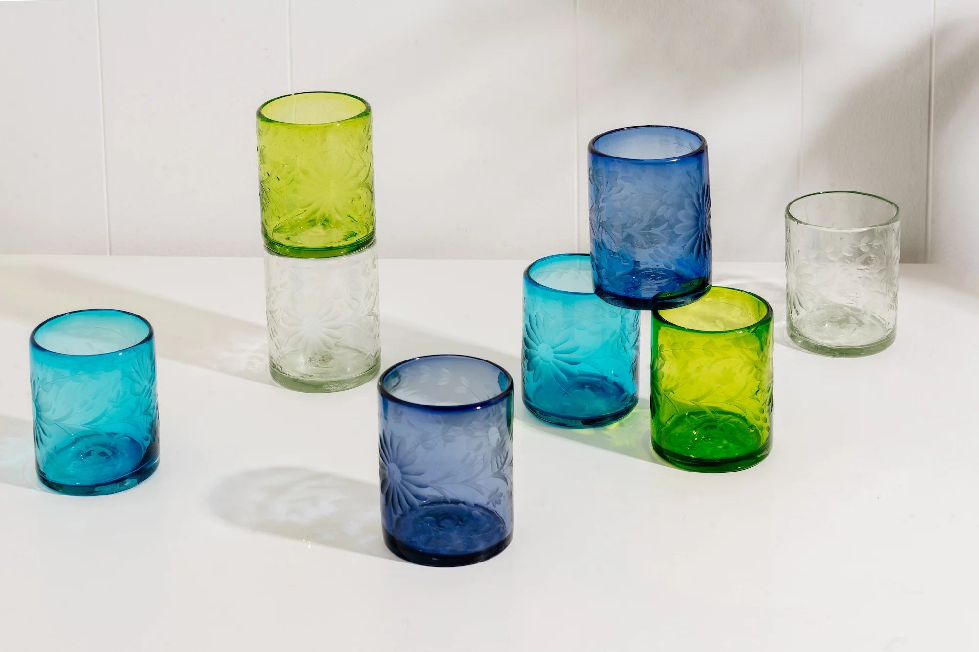 Set of colorful fair trade glass tumblers on a white surface with a light gray background | Global Goods Partners