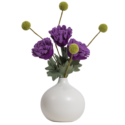 White vase with purple flowers and green stems on a white background | Global Goods Partners
