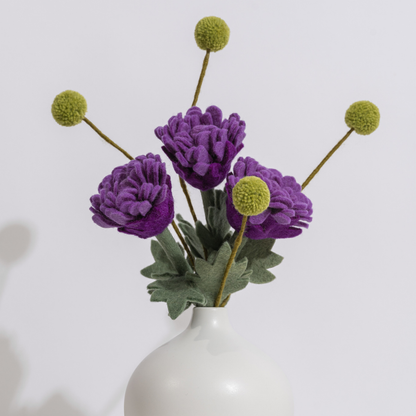 Purple flowers with green stems in a white vase on a light gray background | Global Goods Partners