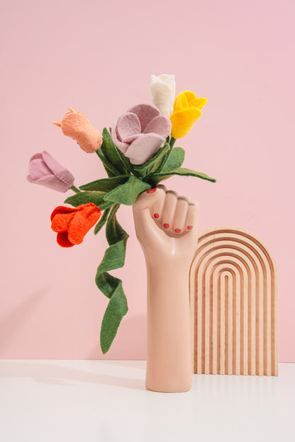 Handmade felt flower bouquet in a hand-shaped vase against a pink background | Global Goods Partners