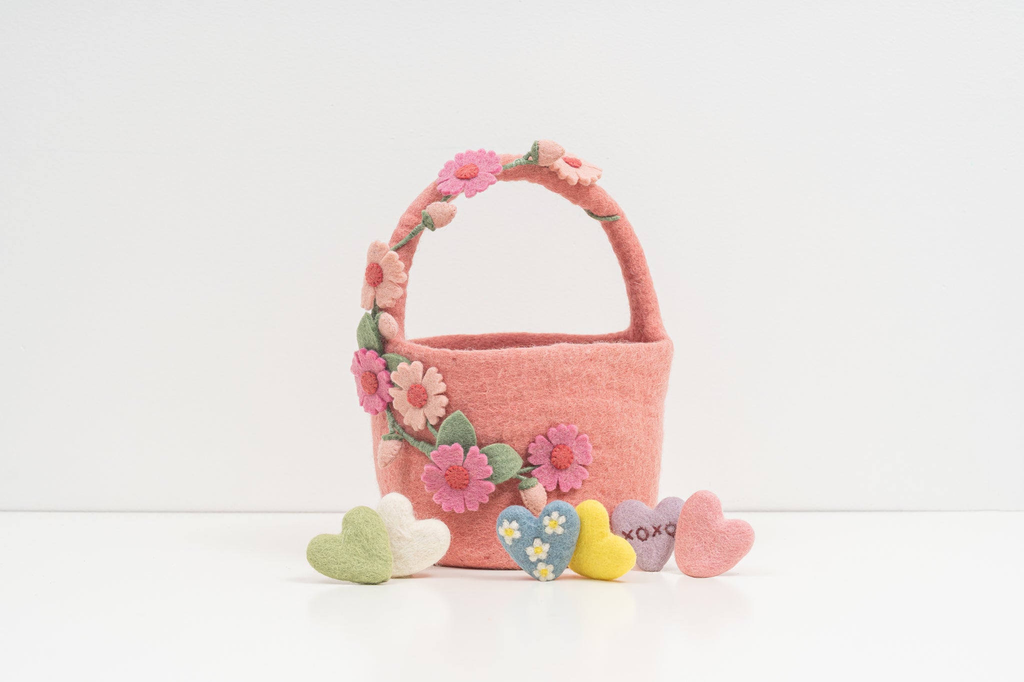 Pink felt basket with floral decorations and heart-shaped toys on a white background. fair trade kids gift | Global Goods Partners